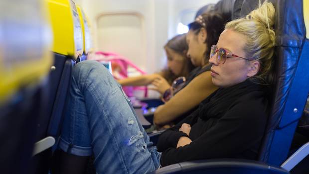 Passagier zit ongemakkelijk met de knieën tegen de stoel voor haar in een volle economyrij